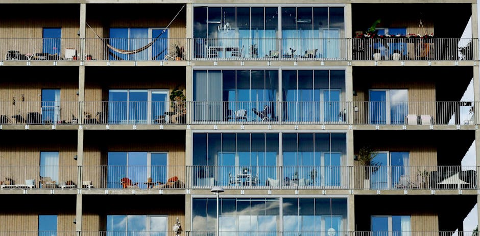 Facade of a modern residential building featuring glass windows, balconies, and metal railings.