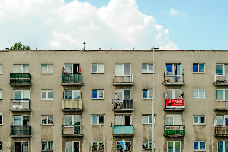 Facade of an urban apartment building with multiple balconies under blue sky.