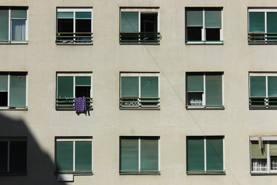 A minimalist view of a modern apartment building facade with repetitive window pattern.